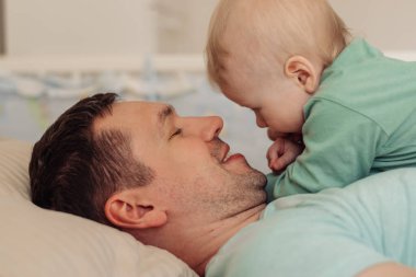 Genç ve mutlu bir baba, oğluyla birlikte yatar. Birlikte zaman geçirir. Aile kavramı. Babalar günü kavramı..