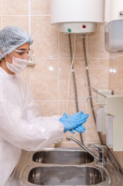 Koruyucu giysi, maske ve eldiven giyen sağlık çalışanları tıbbi araçları sterilize ederler. Coronavirüs ve tıbbi konsept.