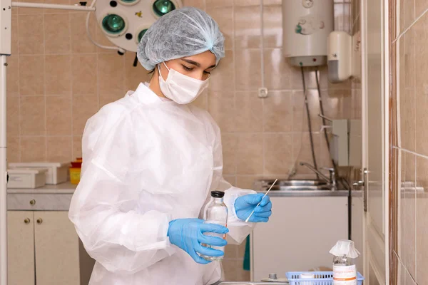 Medical worker in protective clothing,mask and gloves sterilizes medical instruments in the medical office.Coronavirus and medical concept.