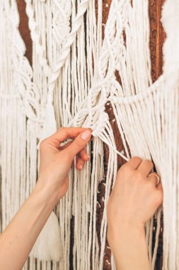 Bir ev atölyesinde makrome ören kadınların ellerini kapat. Ev dekorasyonu. El yapımı kavram..