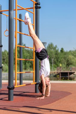 Beyaz tişörtlü, siyah şortlu ve beyaz spor ayakkabılı genç bir kadın spor için içeri giriyor, açık spor salonunda egzersiz yapıyor. Açık hava sporları, sağlıklı yaşam tarzı..