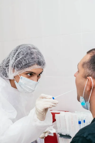 A medical worker taking mouth swab from middle-aged man to test for possible coronavirus infection in clinic.Medical and coronavirus concept.