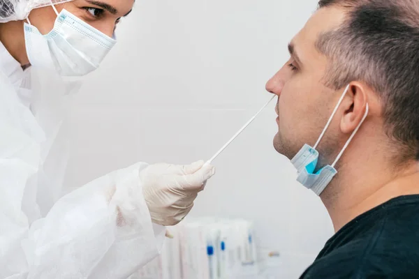 A medical worker taking a nasal swab from middle-aged man to test for possible coronavirus infection in clinic.Medical and coronavirus concept.