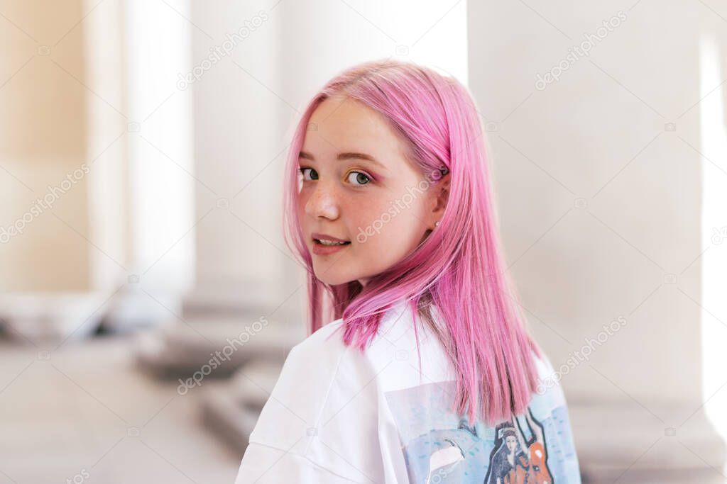 Portrait of a positive pink-haired teenage girl in a white T-shirt.Street style.Summer concept.Generation Z style.Copy space for text.