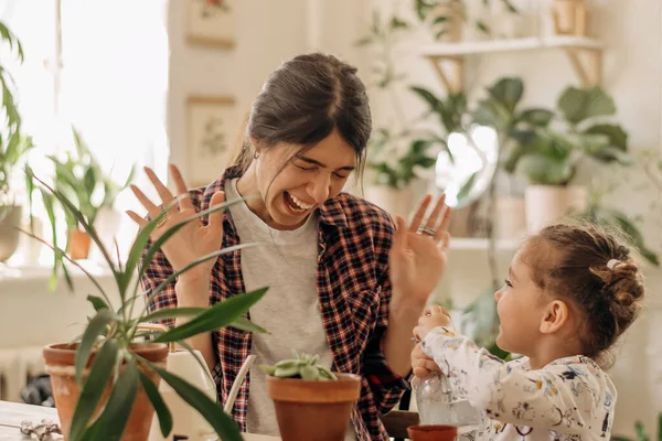 Ung Glad Blandras Kvinna Med Liten Dotter Planterar Krukväxter Hemma — Stockfoto