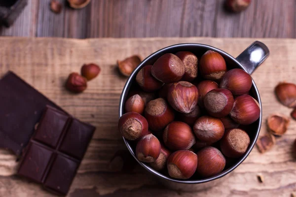 Bitar av choklad med olika nötter på ett träbord — Stockfoto