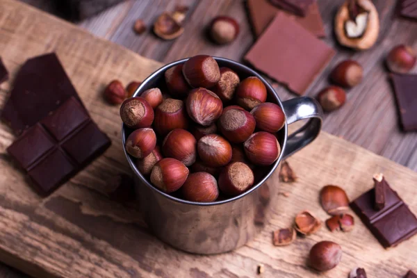 Schokoladenstücke mit verschiedenen Nüssen auf einem Holztisch — Stockfoto