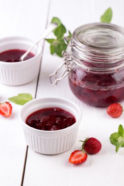 Ahşap arka planda bir kavanozda çilek reçeli