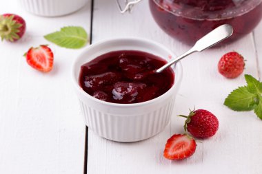 Ahşap arka planda bir kavanozda çilek reçeli