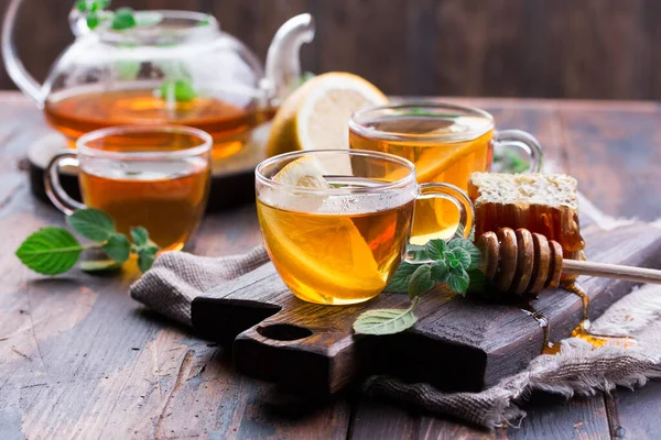 Průhledný šálek čaje s medem a mátou na dřevěném pozadí — Stock fotografie
