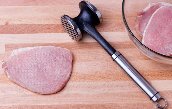 Ruwe varkensvlees schnitzel met vlees tenderizer op houten bord — Stockfoto