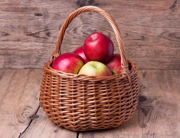 Fresh red apples in basket over wooden background — Stock Photo, Image