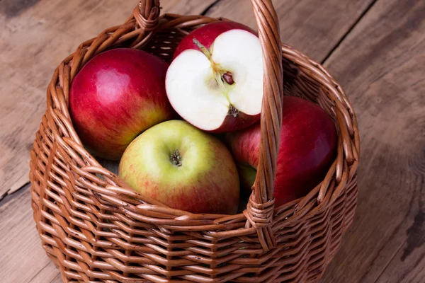 Fresh red apples in basket over wooden background — Stock Photo, Image