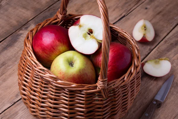 Fresh red apples in basket over wooden background — Stock Photo, Image