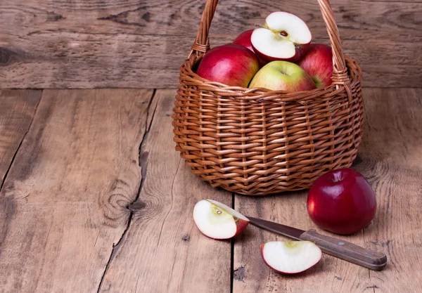 Fresh red apples in basket over wooden background — Stock Photo, Image
