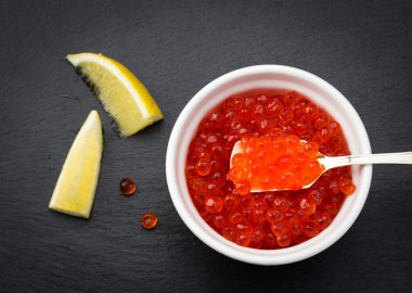 Somon havyar ayakta siyah arduvaz plaka üzerinde limon ve beyaz kase