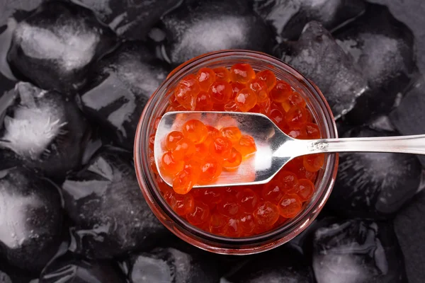 Somon havyar ayakta ortasında siyah arduvaz plaka üzerinde buz küpleri ile Cam Kavanoz