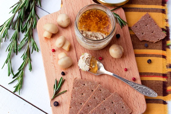 Chicken pate in jar and crispbread on wood cutting board — Stock Photo, Image