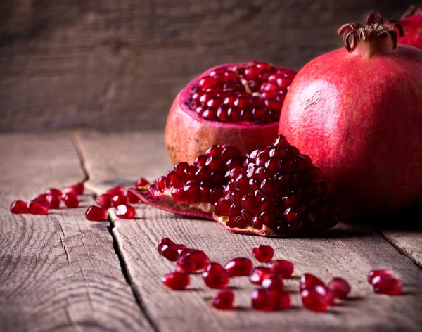 Some red pomegranates on old wooden table — Stock Photo, Image