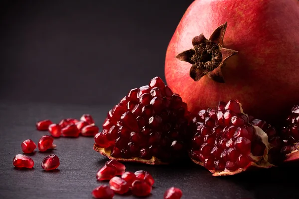 Některé červená granátová jablka na černé břidlicové desky — Stock fotografie
