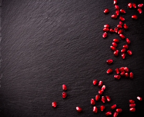 Siyah arduvaz arka plan üzerine nar taneleri