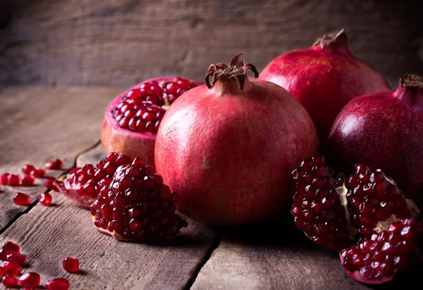 Some red pomegranates on old wooden table — Stock Photo, Image