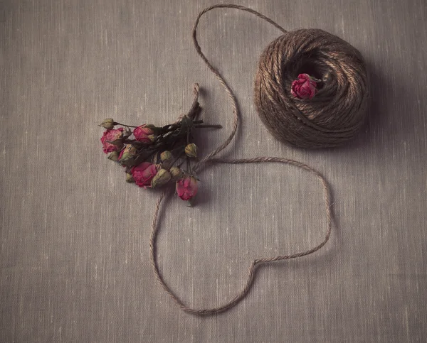 Herzförmige Naturschnur mit einem Strauß getrockneter Rosen — Stockfoto