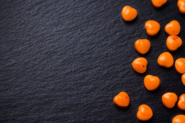 Turuncu kalp hapları veya şeker grunge siyah arduvaz arka plan üzerinde şeklinde. Kopya alanı.