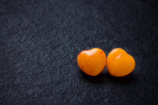 Dva oranžové srdce tvar pilulky nebo bonbóny na grunge černé břidlicové pozadí. Kopírovat prostor. — Stock fotografie