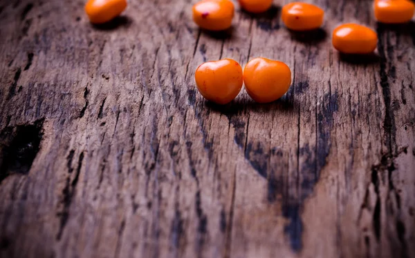 Orange, red heart shaped pills or candy on vintage wooden background. Copy space. — Stock Photo, Image