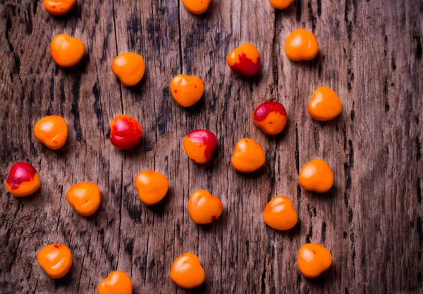 Orange, red heart shaped pills or candy on vintage wooden background. — Stock Photo, Image