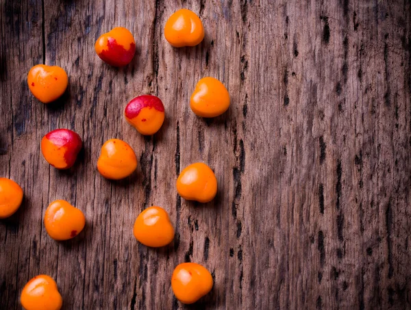 Orange, red heart shaped pills or candy on vintage wooden background. Copy space. — Stock Photo, Image