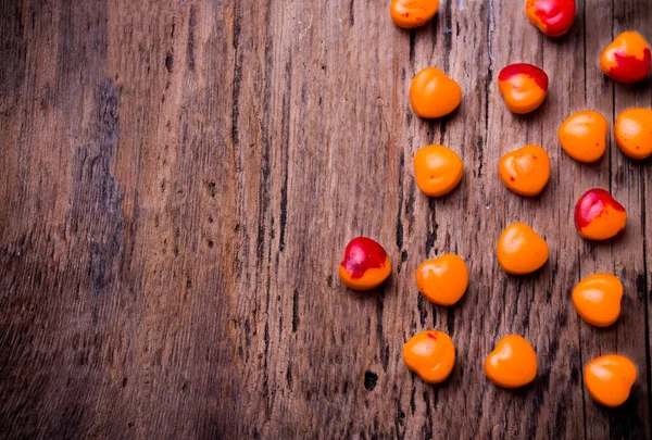 Orange, red heart shaped pills or candy on vintage wooden background. Copy space. — Stock Photo, Image