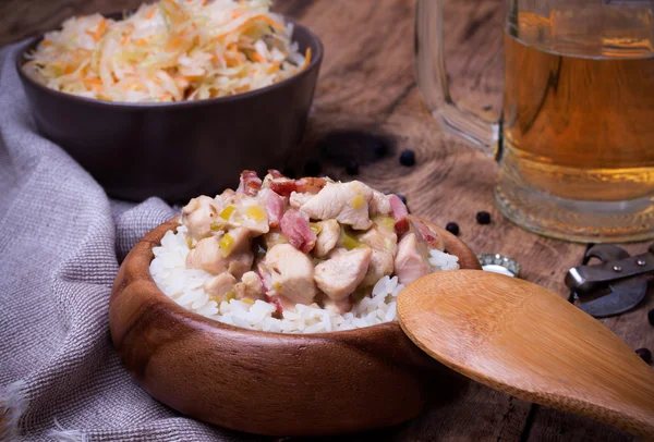 Stufato di pollo con riso, crauti e birra su scrivania in legno rustico — Foto Stock