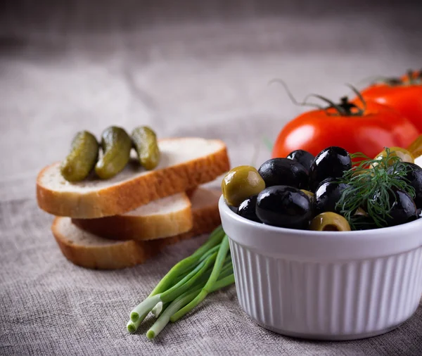 Rode tomaten, zwarte en groene olijven in witte kom op jute stof — Stockfoto