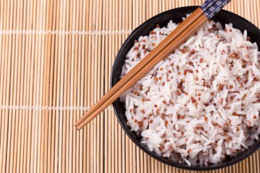 Beyaz pirinç ve quinoa ile bambu hasır üzerinde yemek çubukları kase.