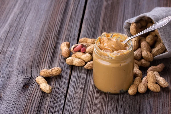 Fresh made creamy Peanut Butter in a glass jar — Stock Photo, Image