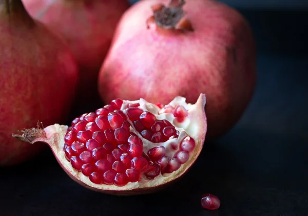 Some red pomegranates on black slate plate — Stock Photo, Image