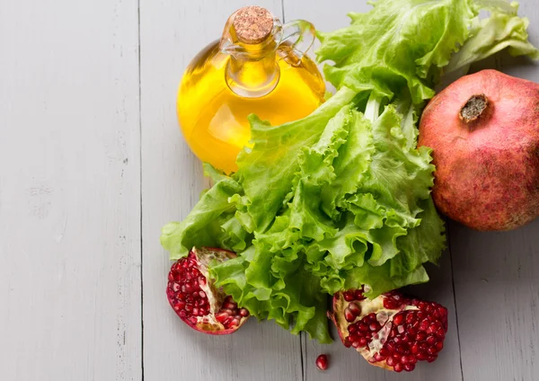 Healthy veggie salad ingridients. Pomegranate, lettuce and olive oil. — Stock Photo, Image