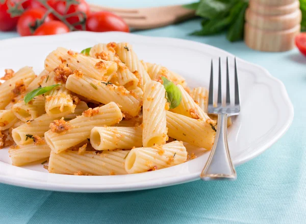 Πλάκα του penne ζυμαρικών με ψωμί ψίχουλα, βασιλικό και ντοματίνια. — Φωτογραφία Αρχείου