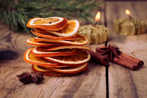 Gesneden gedroogde oranje, kaneelstokjes, anijs sterren en kaars met pine brunch — Stockfoto