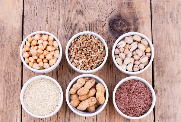 Tigelas de várias leguminosas e sementes. Lentilhas, sementes de sésamo, pistache, linhaça, passas, amendoim, grão de bico . — Fotografia de Stock