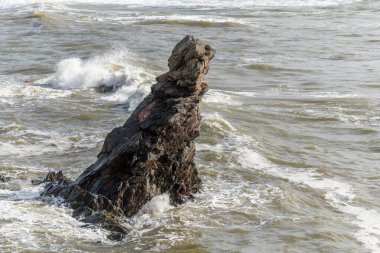Yazın Fransız sahillerindeki Atlantik Okyanusu 'nda bir kayanın üzerinde dalgalar kırılıyor..