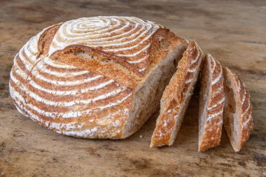 Eski ahşap bir masanın üzerinde büyülenmiş unla taze ekmek.