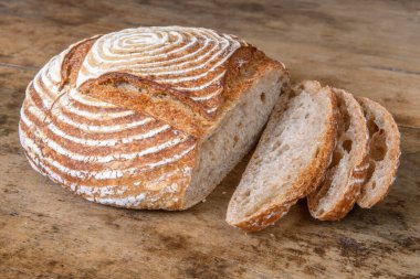 Eski ahşap bir masanın üzerinde büyülenmiş unla taze ekmek.