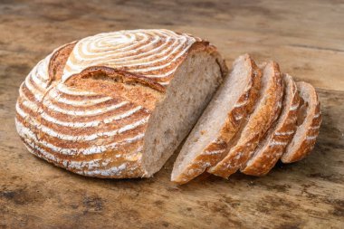 Eski ahşap bir masanın üzerinde büyülenmiş unla taze ekmek.