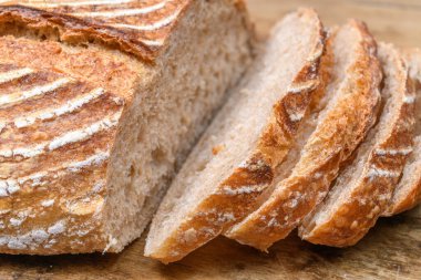 Eski ahşap bir masanın üzerinde büyülenmiş unla taze ekmek.