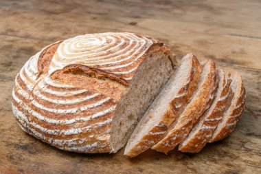 Eski ahşap bir masanın üzerinde büyülenmiş unla taze ekmek.