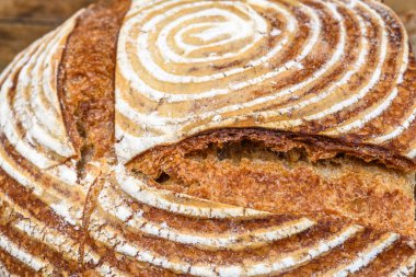 Eski ahşap bir masanın üzerinde büyülenmiş unla taze ekmek.