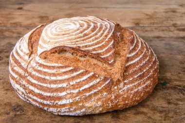 Eski ahşap bir masanın üzerinde büyülenmiş unla taze ekmek.